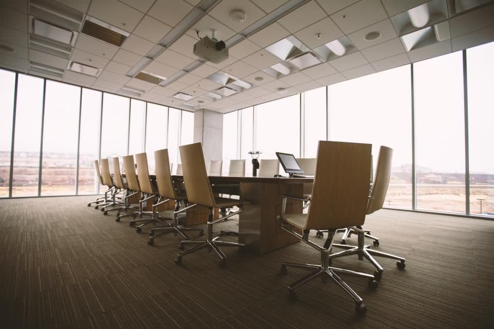 An empty boardroom on a high floor, long table and chairs facing a glazed wall.